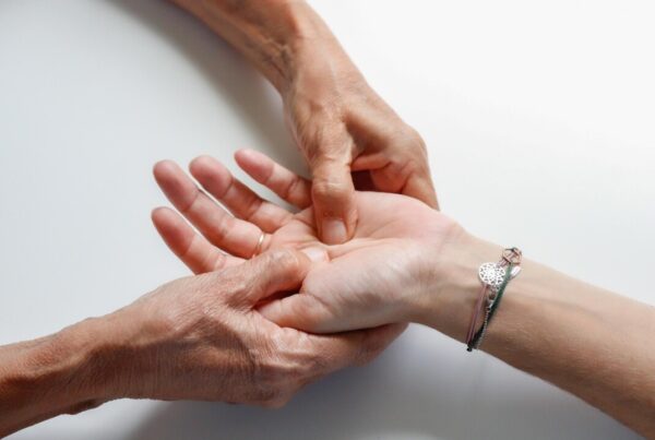Two hands clasped in a comforting, supportive gesture on a white background.