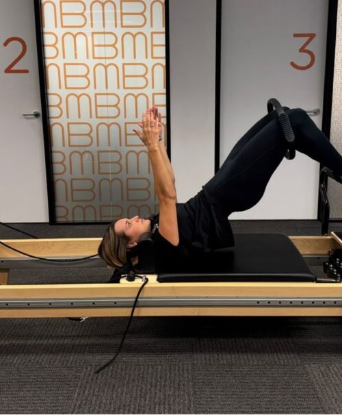 Physiotherapist guiding a client through glute strengthening Pilates exercises on the Reformer at Bend + Mend, Sydney CBD