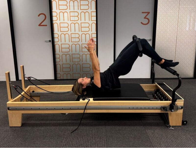 Physiotherapist guiding a client through glute strengthening Pilates exercises on the Reformer at Bend + Mend, Sydney CBD