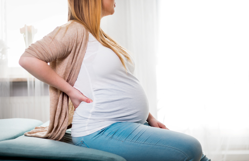 a woman holding her sore back while pregnant