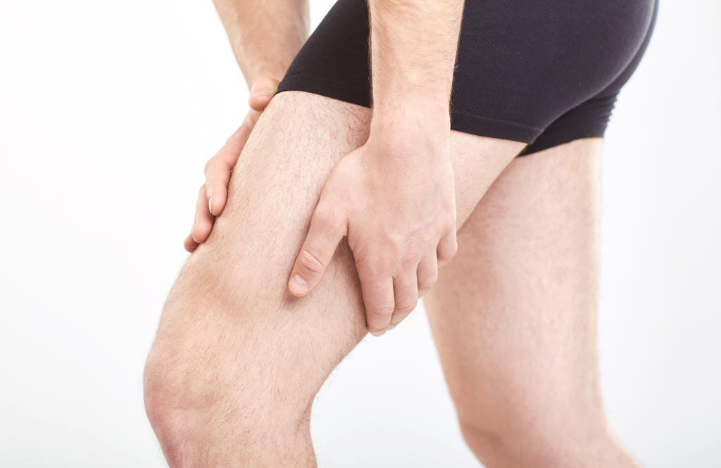 man holding his strained leg muscle