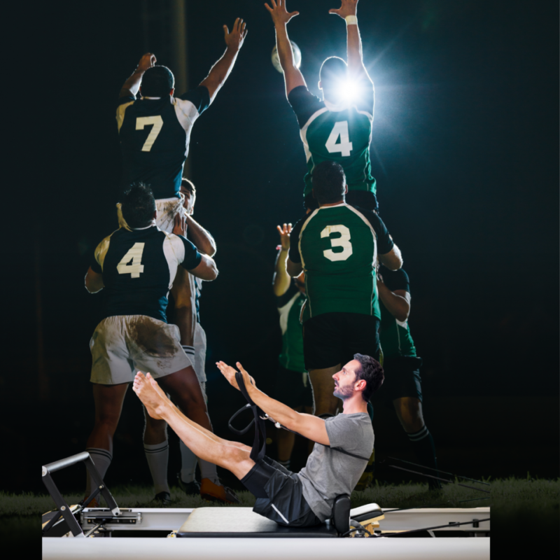 Man doing leg-raise on a Pilates reformer while a rugby team jumps in celebration behind him in a gym. (informative)