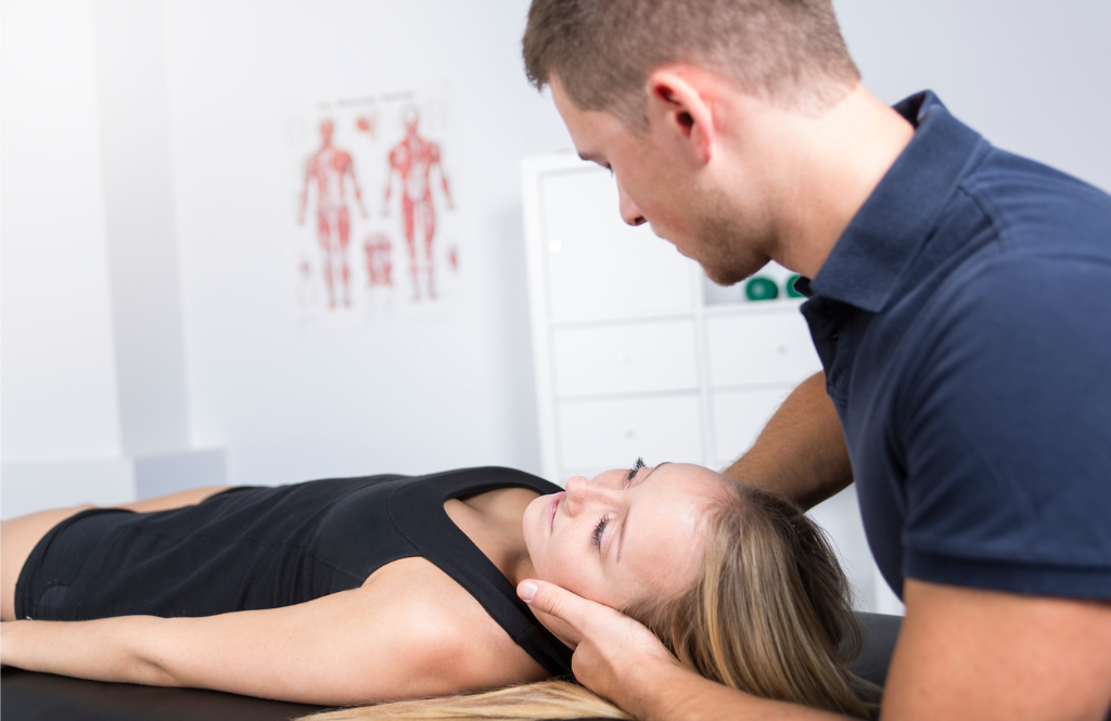 Physiotherapist supporting a woman's head as she lies on a treatment table during a neck examination.